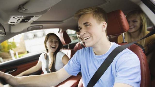 Teenagers enjoy a car ride, smiling and laughing, promoting safe and joyful driving experiences.