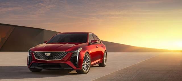 Red luxury sedan parked against a sunset background, showcasing its sleek design and modern elegance.