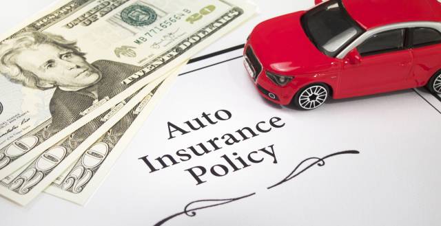 Toy car, cash, and auto insurance policy document, representing car insurance costs and payment.
