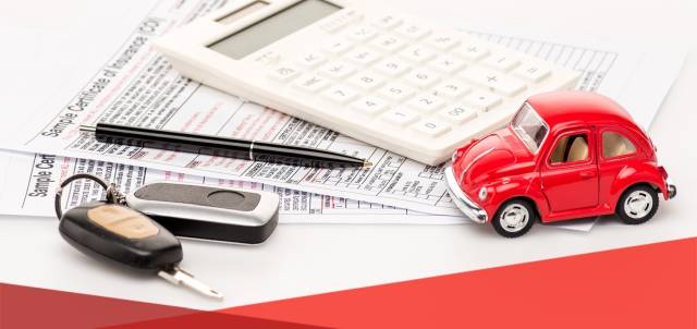 Calculator and toy car on insurance forms with pen and car keys, symbolizing car insurance and financial calculations.