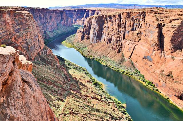 Breathtaking view of the Colorado River winding through the Grand Canyon's steep cliffs under a clear blue sky.