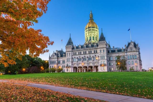 Connecticut State Capitol building during autumn, with vibrant foliage and a clear blue sky.