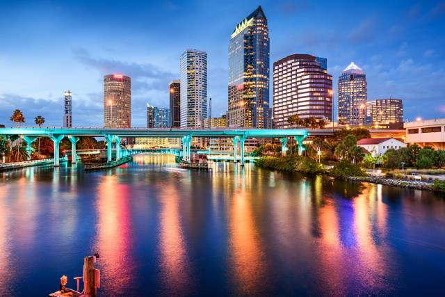 Tampa skyline at dusk with colorful light reflections on the river, showcasing modern skyscrapers and vibrant city life.