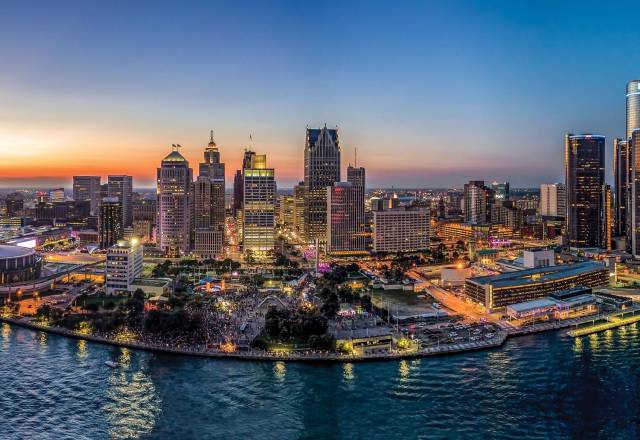Aerial view of a vibrant city skyline at sunset, with modern skyscrapers and a waterfront, showcasing urban life.