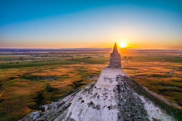Sunset over Chimney Rock in Nebraska, highlighting its iconic sandstone spire against vibrant countryside.
