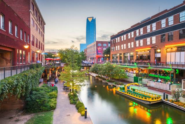Downtown cityscape with canal boat ride, lively buildings, and sunset sky. Ideal travel destination for urban explorers.