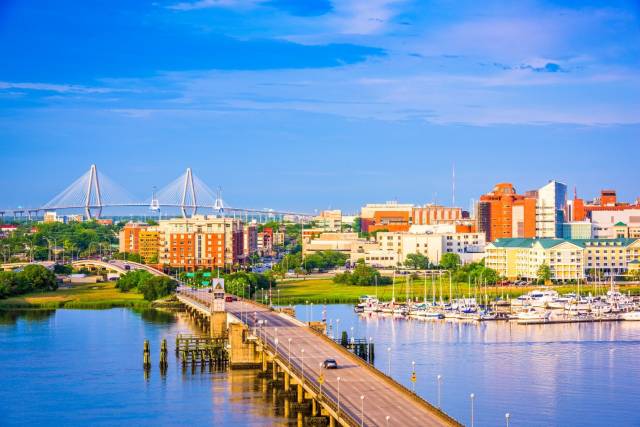 Charleston cityscape with bridge and marina, under a blue sky. Scenic waterfront view showcasing iconic landmarks.