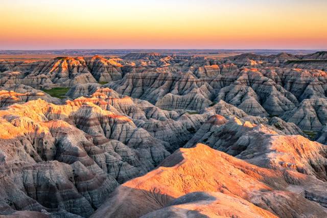 Sunset over Badlands National Park's rugged landscape, showcasing striking rock formations and vibrant colors.